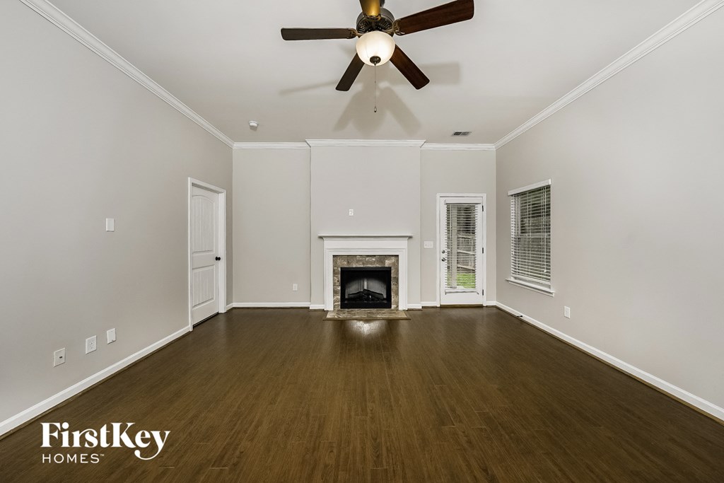 A spacious room with a fireplace and a ceiling fan.