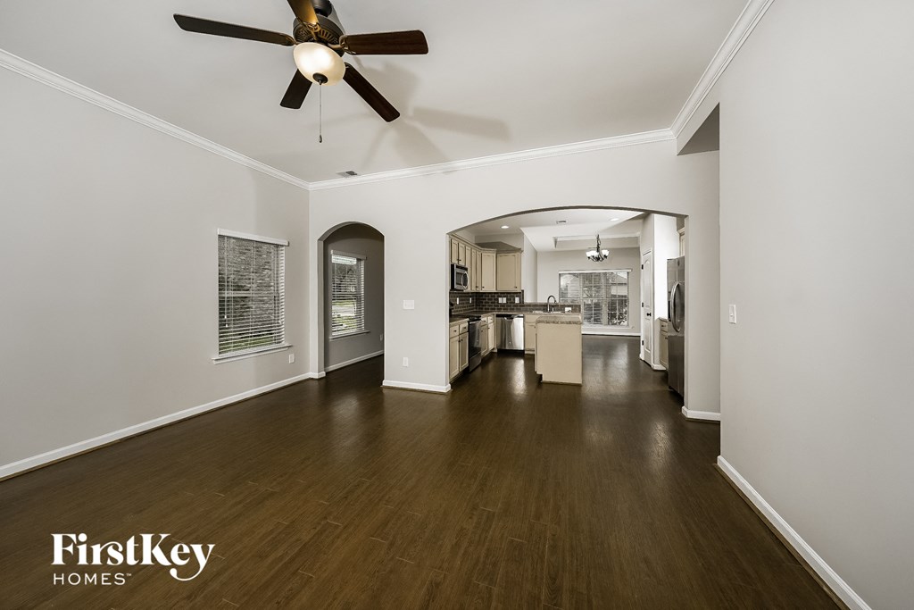 A spacious room with a fan and wooden floors.