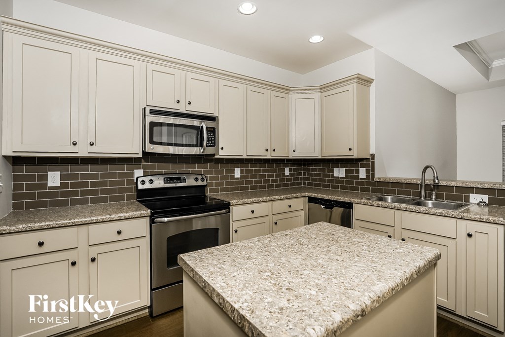 A kitchen with a granite countertop and a stove top oven.