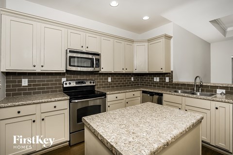 A kitchen with a granite countertop and a stove top oven.