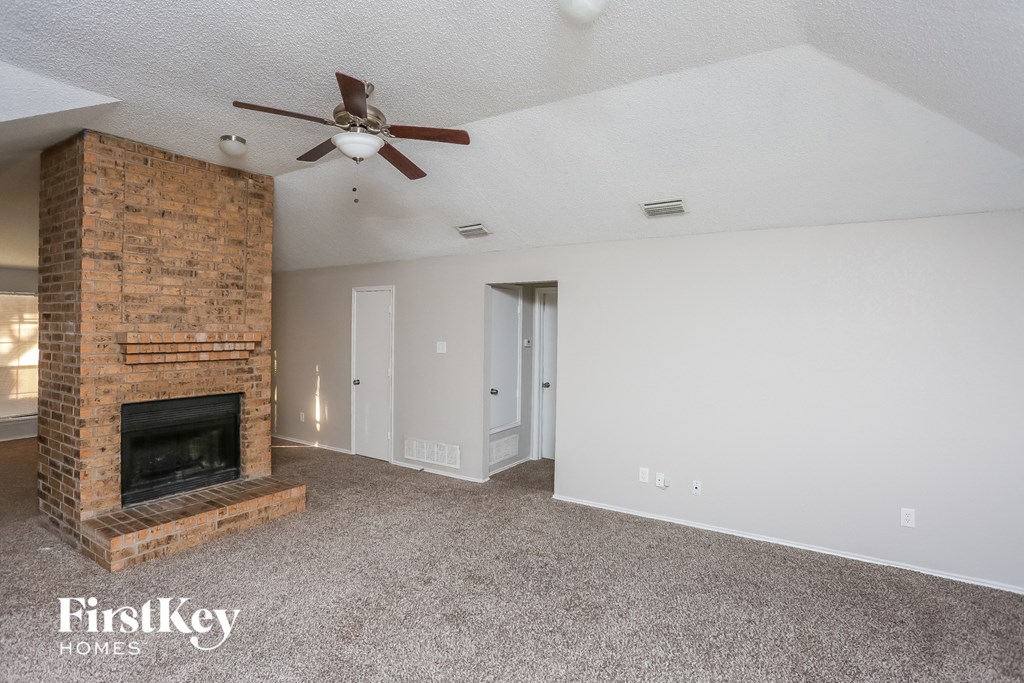 a living room with a brick fireplace and a ceiling fan