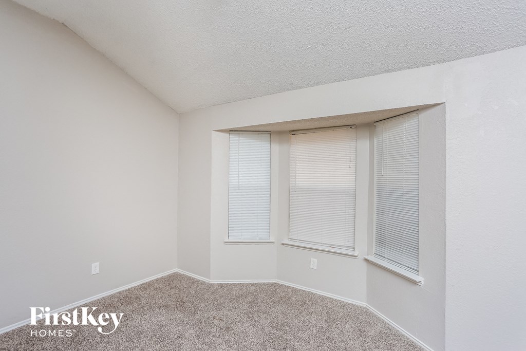 a bedroom with three windows and a carpeted floor