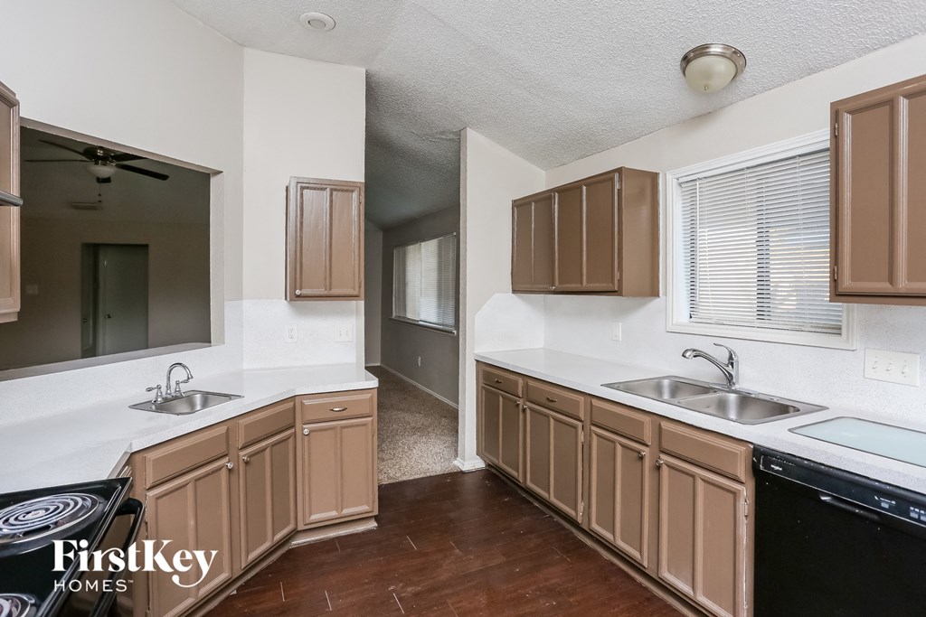 a kitchen with white counter tops and wooden cabinets and a black dishwasher