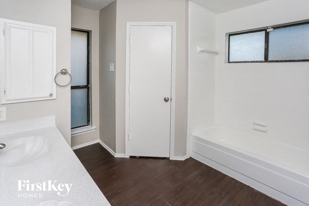 a white bathroom with a tub and a sink and a door