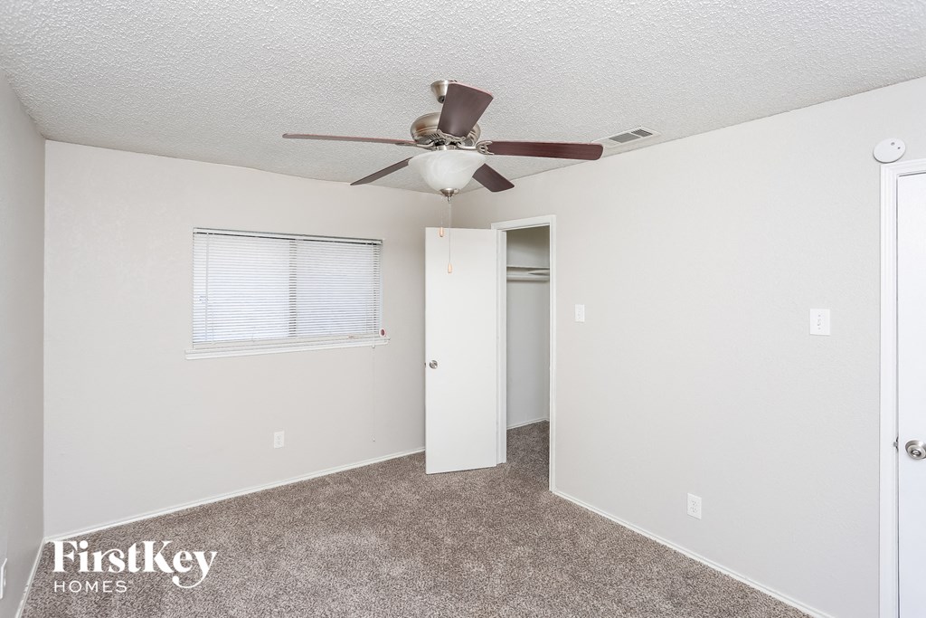 a bedroom with a ceiling fan and a door to a closet