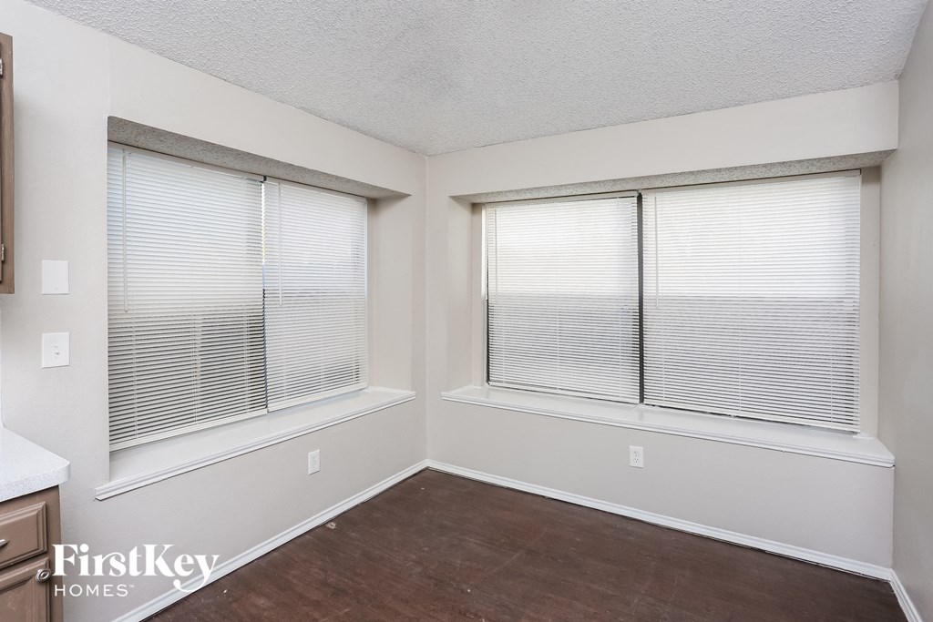 an empty room with three windows and a wood floor