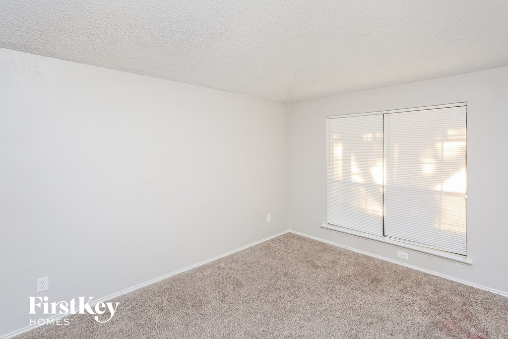 a bedroom with a large window and a carpeted floor