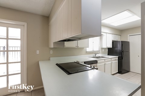 A kitchen with a white counter top and a black stove top.