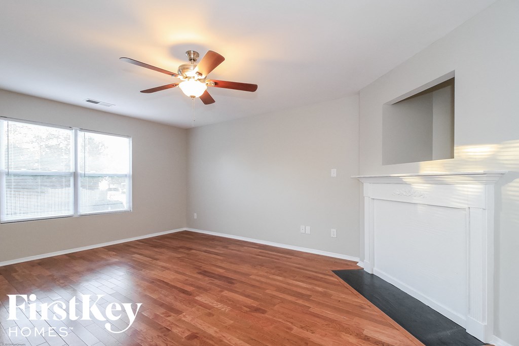 A room with a ceiling fan and wooden flooring.