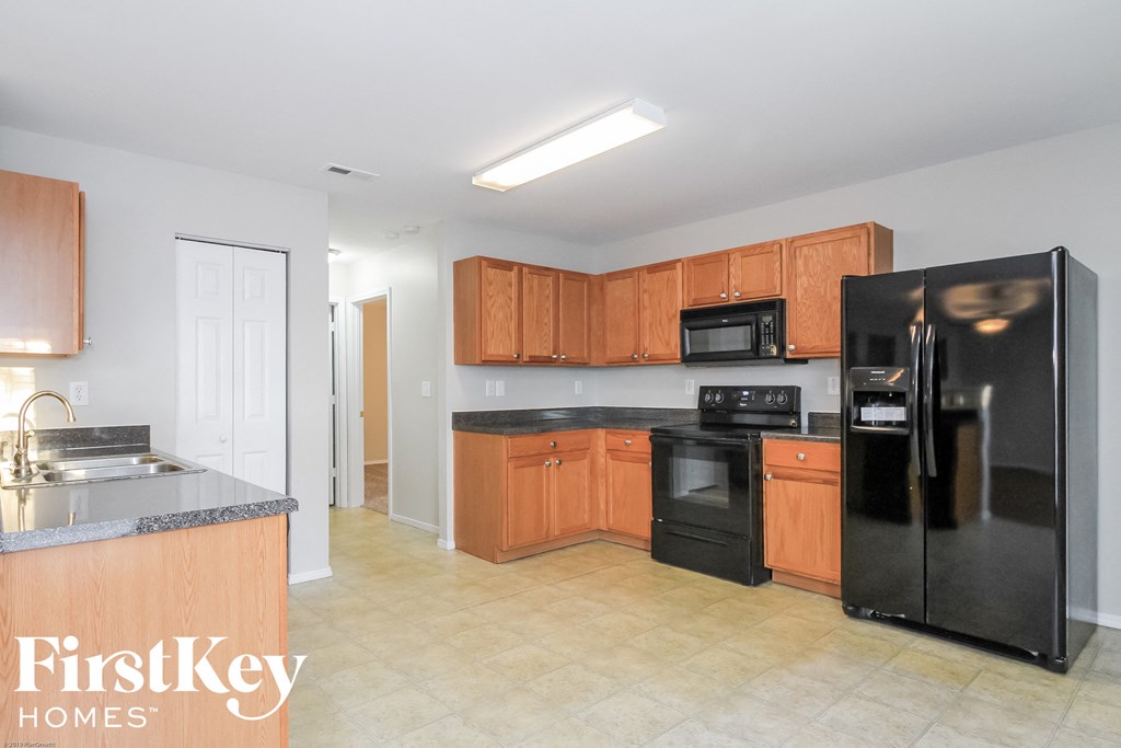A kitchen with black appliances and wooden cabinets.