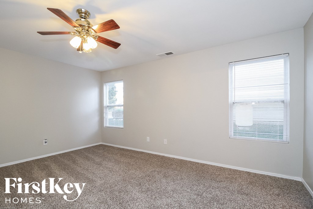 A room with a carpet floor, a ceiling fan, and a window with blinds.