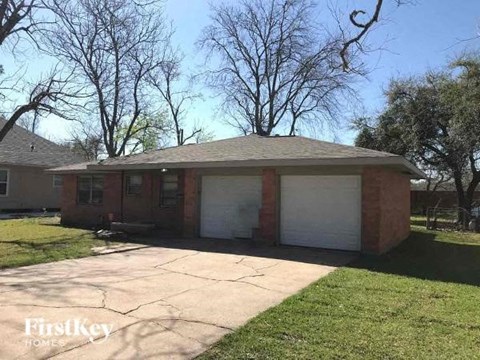 A brick house with a white garage door is for sale.