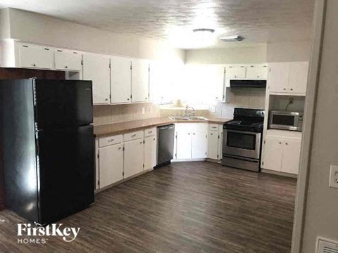 A kitchen with white cabinets and a black fridge.