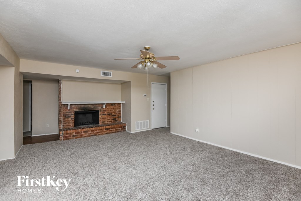 a living room with a brick fireplace and a ceiling fan