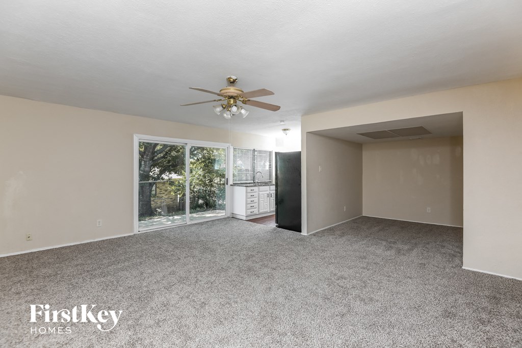 an empty living room with a ceiling fan and a window