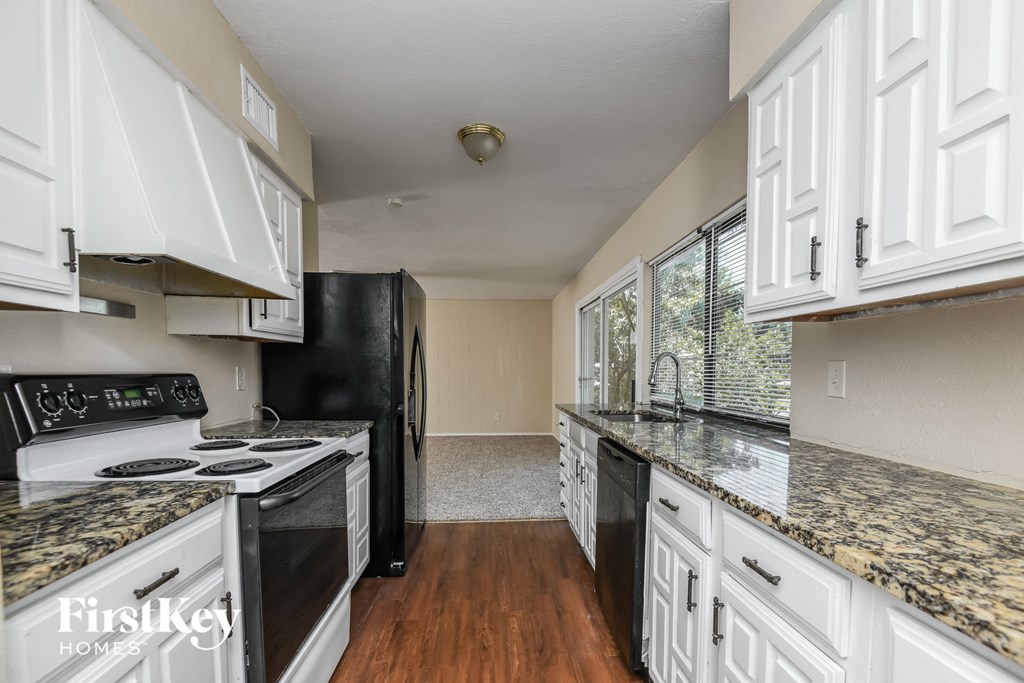 a kitchen with white cabinets and black appliances and granite counter tops