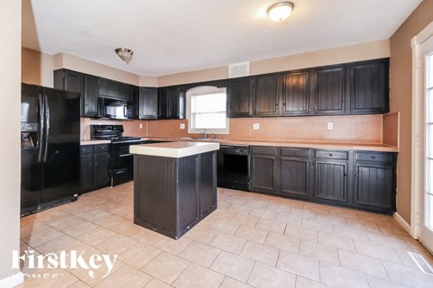 A kitchen with black cabinets and a tiled floor.