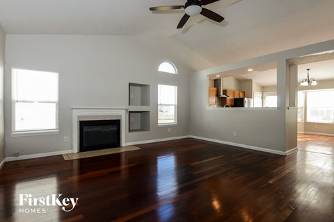 A spacious living room with a fireplace and a fan.