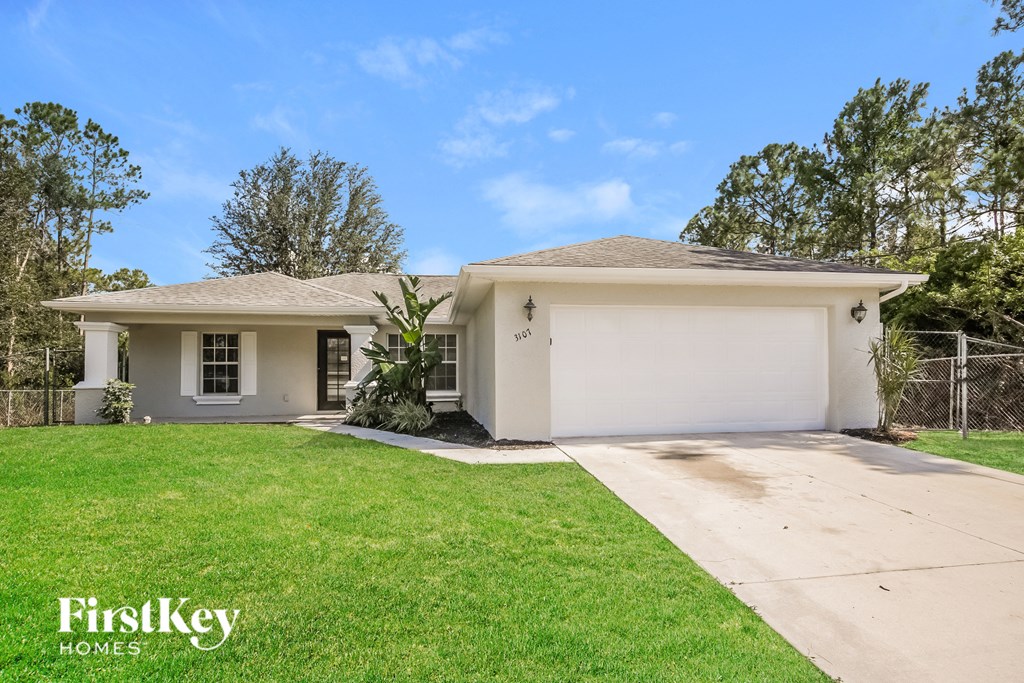 a white house with a lawn and a driveway