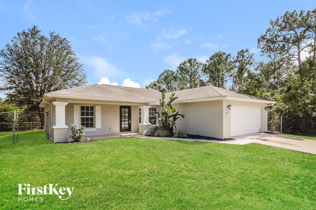 a white house with a green lawn and trees