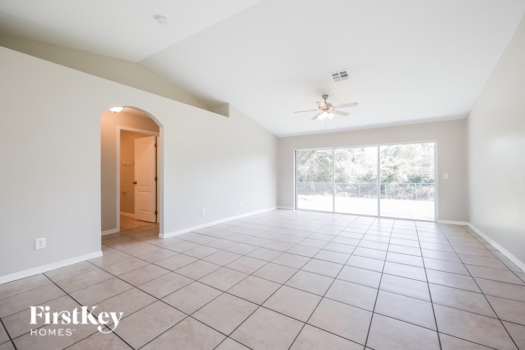 an empty living room with a ceiling fan and a large window