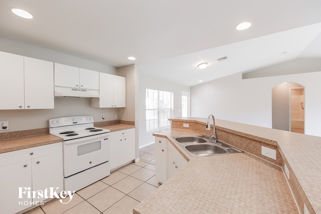 a kitchen with white appliances and counters and a sink