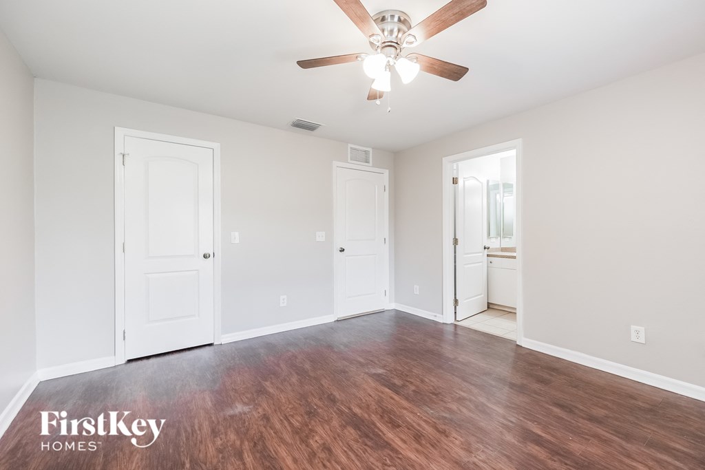 an empty living room with a ceiling fan and wood flooring