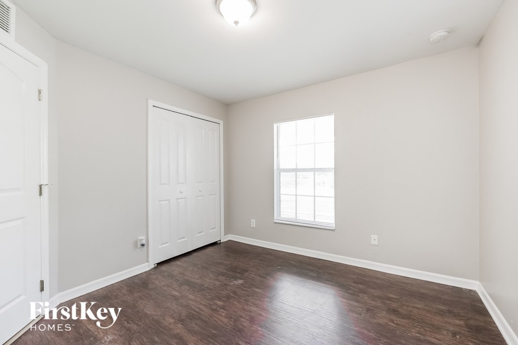 a bedroom with white walls and wood floors and a white door