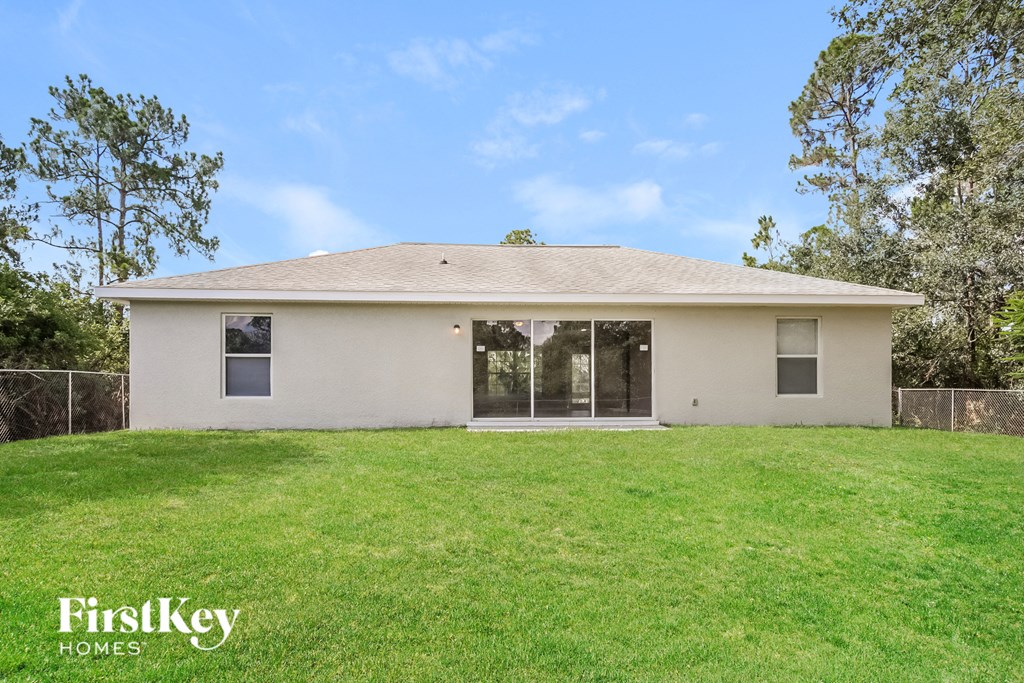 a small white house with a lawn and trees