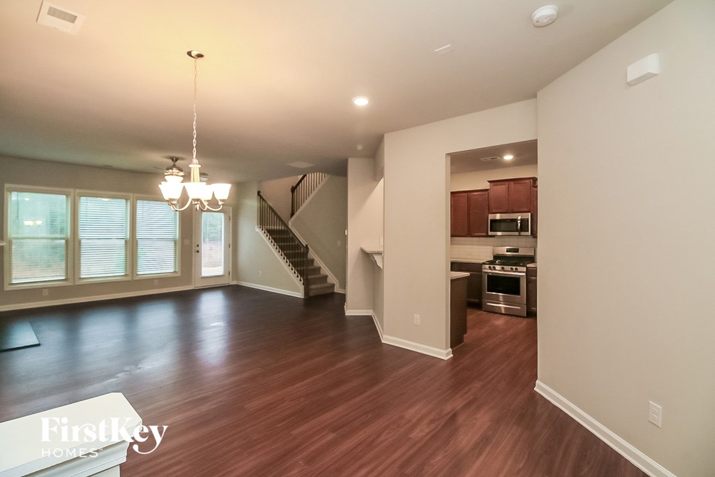 an empty living room and kitchen with wood flooring