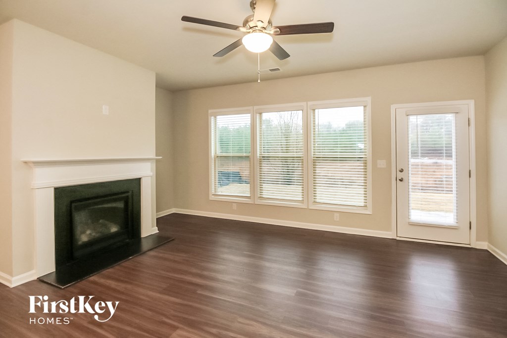 an empty living room with a fireplace and a ceiling fan