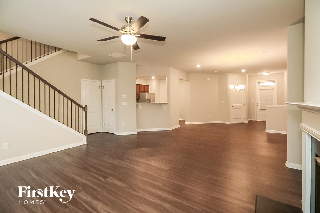 an empty living room with wood floors and a ceiling fan