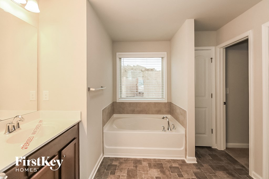 a bathroom with a tub and a sink and a window