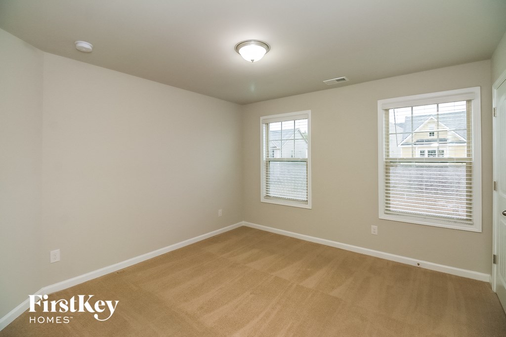 a bedroom with a hardwood floor and two windows