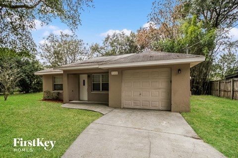 a small tan house with a driveway and a garage door