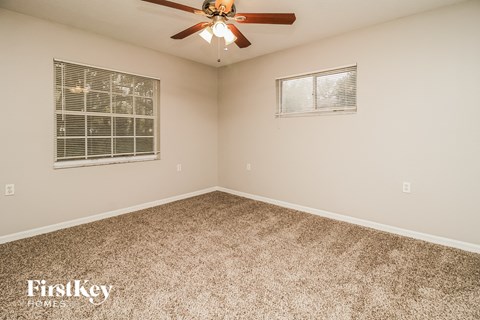 the master bedroom has a ceiling fan and a carpeted floor