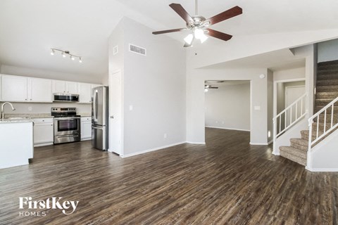 A spacious kitchen with a stainless steel refrigerator and a wooden floor.