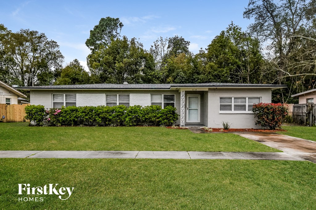 a small white house with a lawn and a sidewalk
