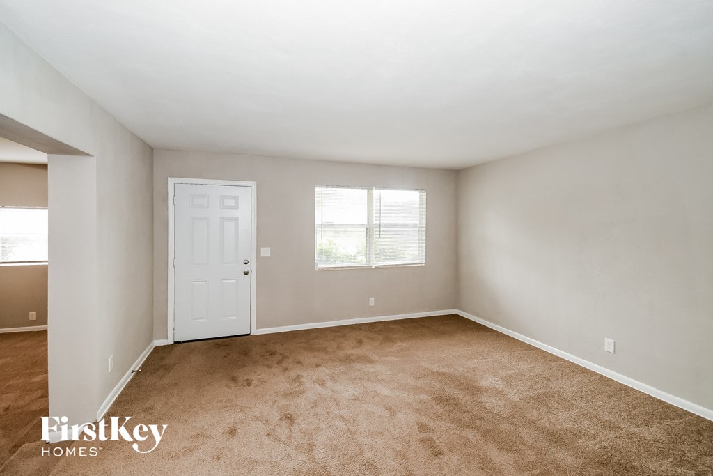 an empty room with a white door and a window