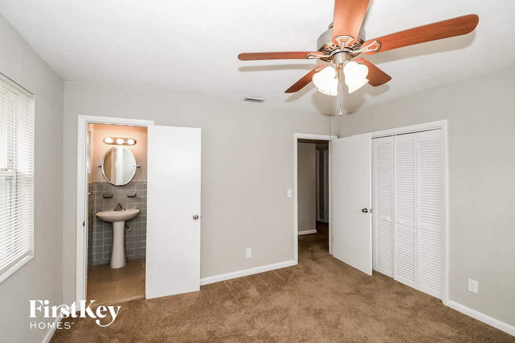 a bedroom with a ceiling fan and a bathroom with a sink