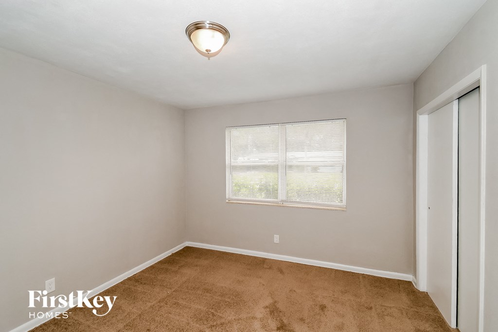 a bedroom with a window and a carpeted floor