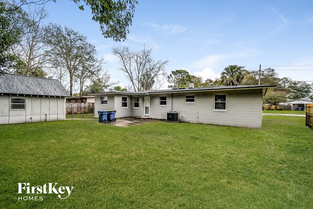 a white house with a grass yard and a blue trash can