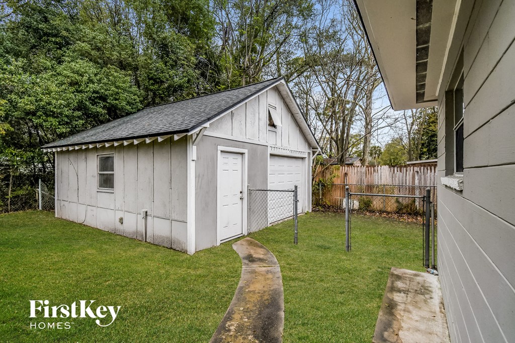 a small white shed in a backyard next to a fence
