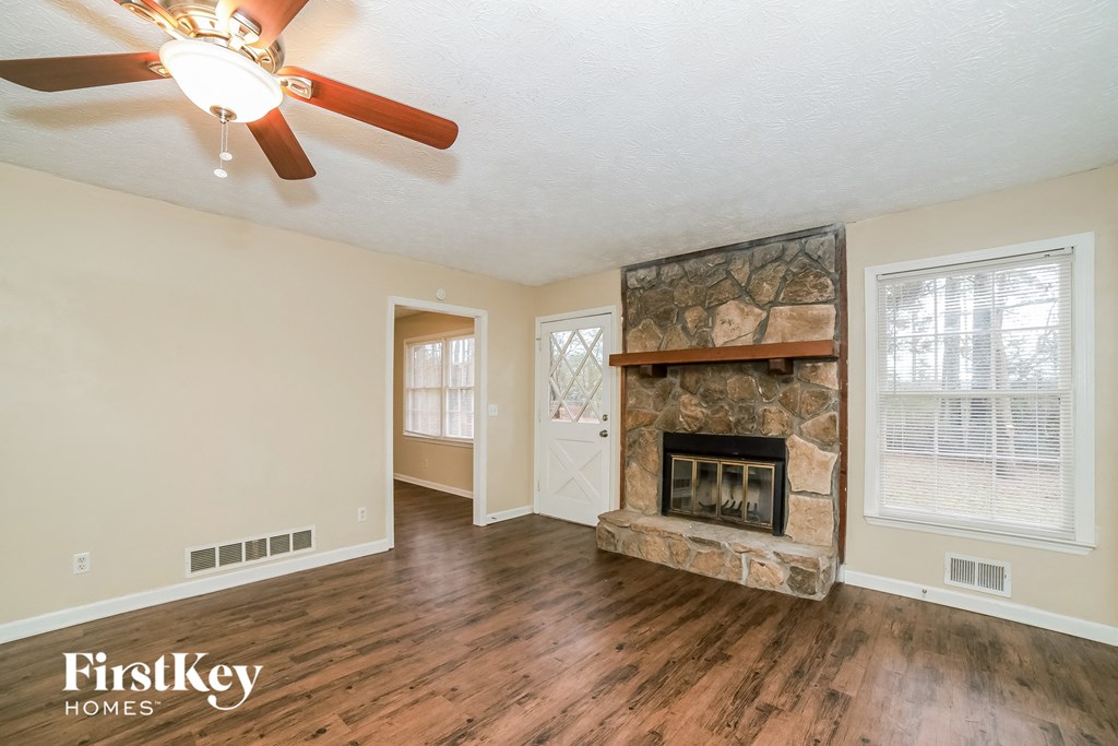 the living room has a stone fireplace and hardwood floors