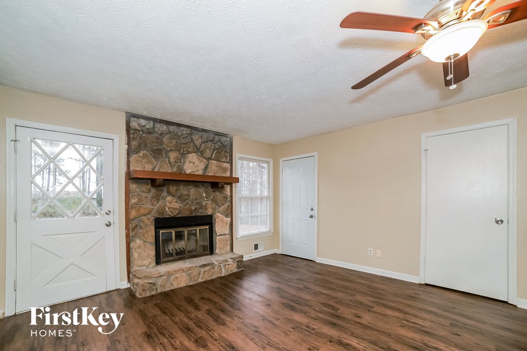 the living room has a stone fireplace and wood flooring