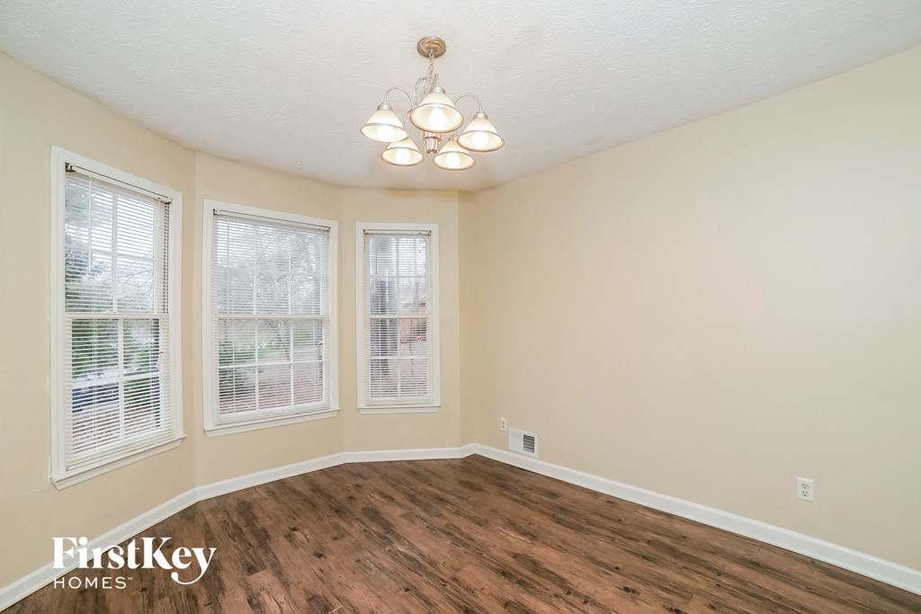 the living room of a home with a hardwood floor and three windows