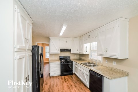 a kitchen with white cabinets and black appliances