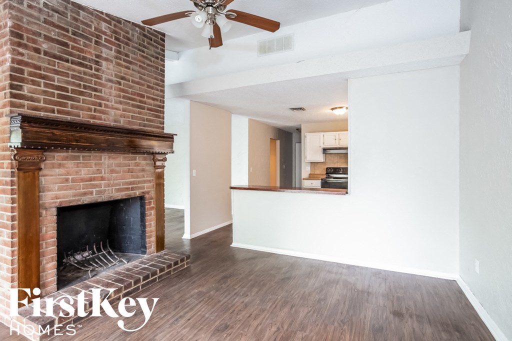 A room with a brick fireplace and a ceiling fan.