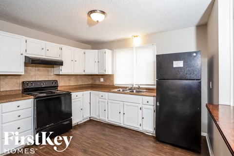 A kitchen with black appliances and white cabinets.