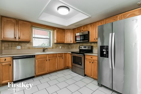 A kitchen with wooden cabinets and a stainless steel refrigerator.